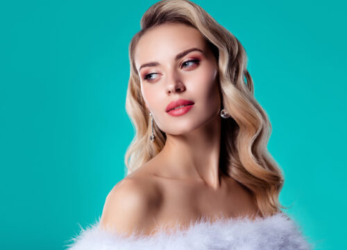 Blonde woman looking like a movie star on a teal background