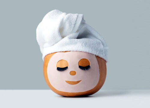 Pumpkin wearing a hydrating face mask on a gray background