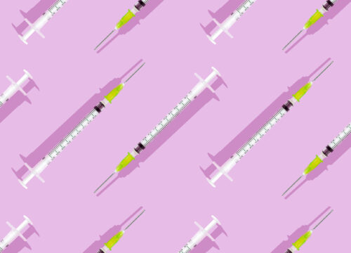 Injectable syringes arranged in a pattern on a pink background