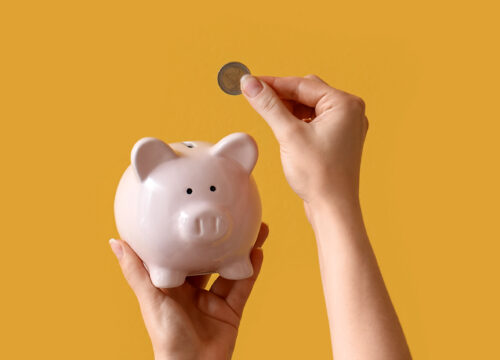 Hand putting money in a piggy bank to save for skin•vestment planning