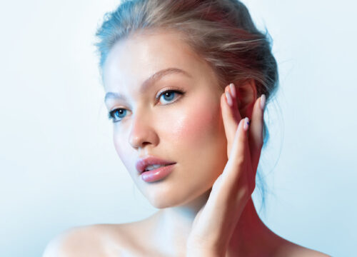 Blonde woman with glowing skin after Total Renewal Facial on a blue background