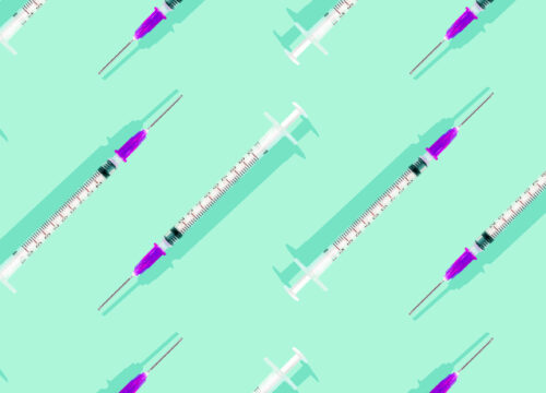 Injectable syringes laid out on a bright minty background